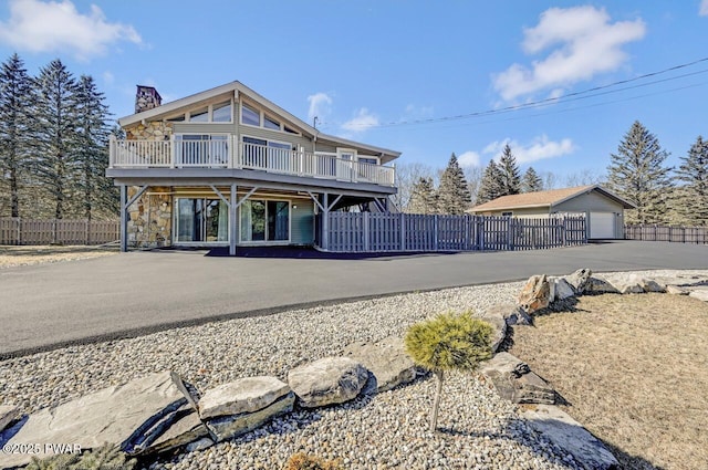 view of front of home featuring a deck, a chimney, and fence