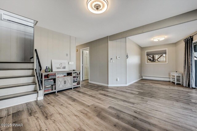 interior space with a baseboard heating unit, stairs, baseboards, and wood finished floors