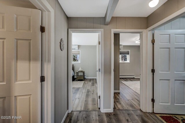 hall featuring a baseboard heating unit, beam ceiling, baseboards, and dark wood finished floors