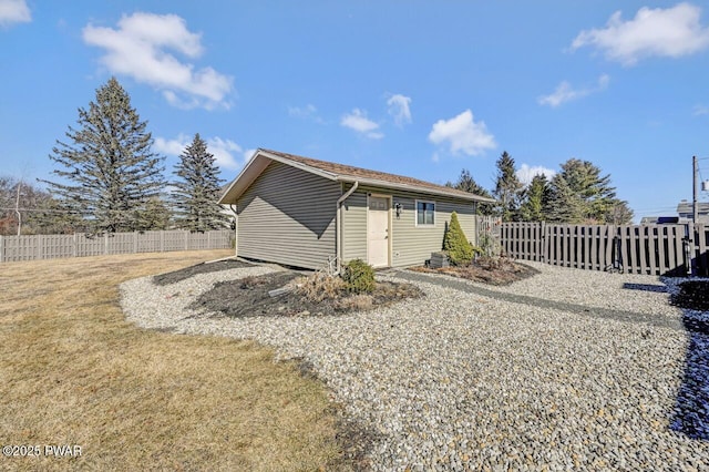 rear view of house with an outbuilding, a lawn, and fence private yard