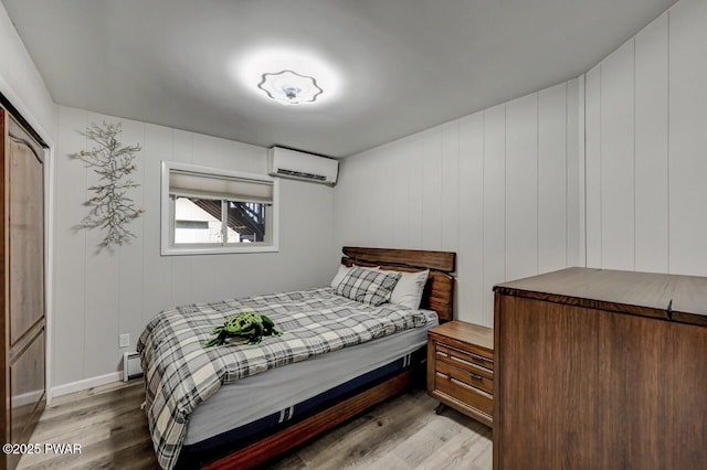 bedroom featuring light wood-style flooring, a wall mounted air conditioner, and a baseboard radiator