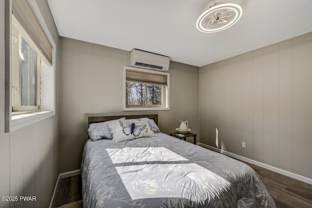 bedroom featuring an AC wall unit, baseboards, and wood finished floors