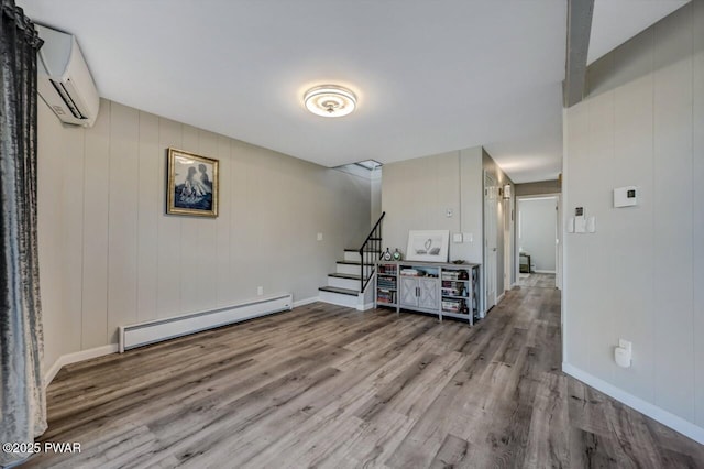 living area with stairway, an AC wall unit, wood finished floors, and a baseboard radiator