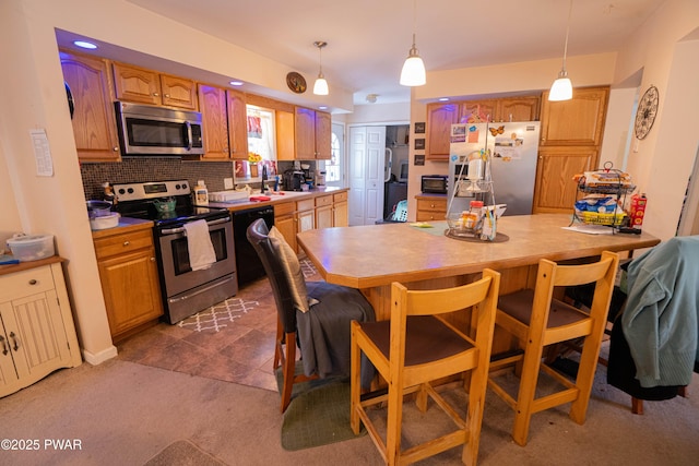 kitchen featuring stainless steel appliances, a breakfast bar, decorative light fixtures, and decorative backsplash