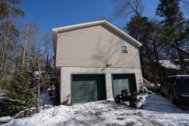 snow covered property featuring an attached garage and stucco siding