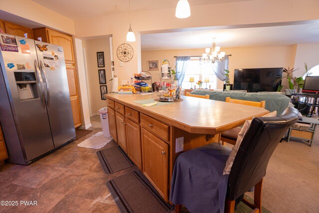 kitchen with a breakfast bar, open floor plan, light countertops, stainless steel refrigerator with ice dispenser, and pendant lighting