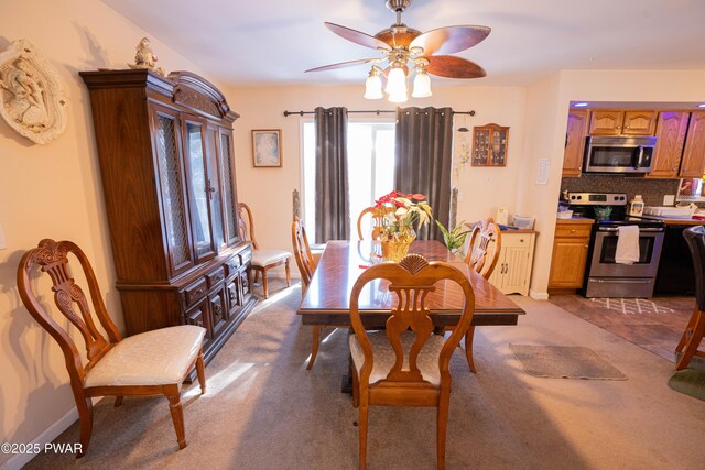 dining area featuring baseboards, dark carpet, and a ceiling fan