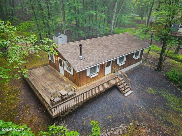 1081 Maple Lake Dr, Bushkill, PA 18324 - rear view of property featuring a wooden deck, a storage unit, a shingled roof, and a forest view