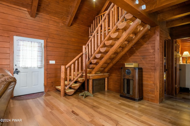 entrance foyer featuring lofted ceiling with beams, light wood-type flooring, wood ceiling, and wooden walls