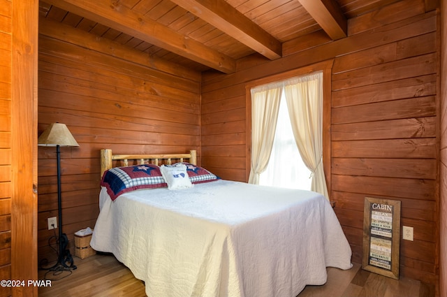 bedroom with wooden walls, hardwood / wood-style floors, beamed ceiling, and wooden ceiling