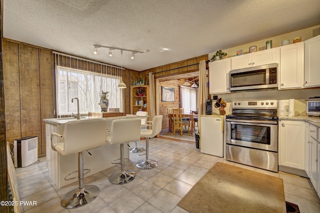 109 Pebble Rock Rd, Lackawaxen, PA 18435 - kitchen featuring white cabinets, a sink, appliances with stainless steel finishes, and wooden walls