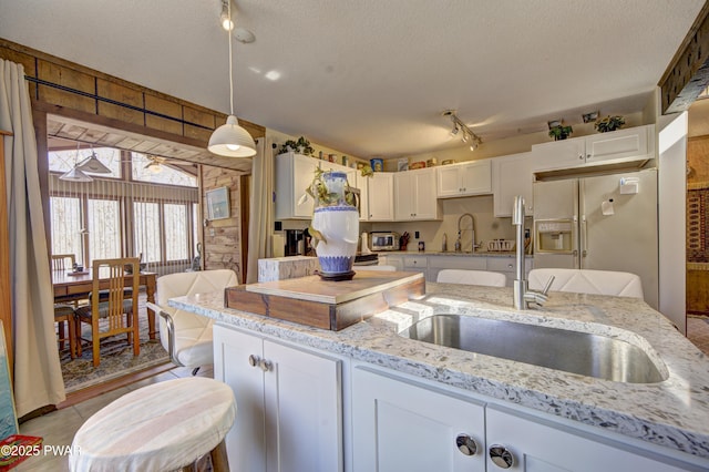 109 Pebble Rock Rd, Lackawaxen, PA 18435 - kitchen with a textured ceiling, white cabinetry, white refrigerator with ice dispenser, and light stone counters