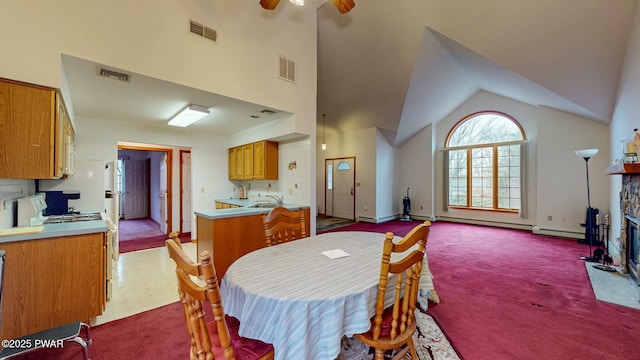 dining area featuring visible vents, carpet floors, high vaulted ceiling, and a fireplace