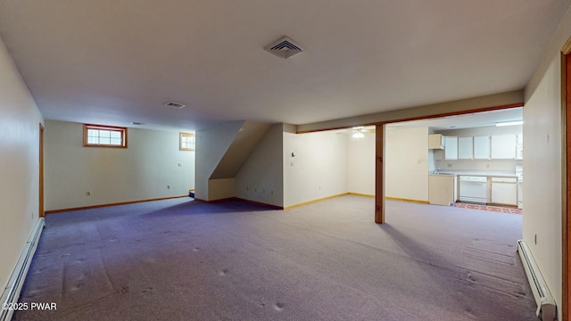 basement with visible vents, light colored carpet, a baseboard heating unit, and a baseboard radiator