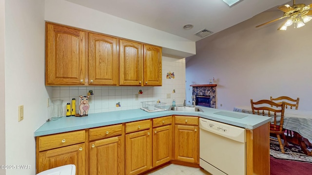 kitchen featuring visible vents, light countertops, a peninsula, white dishwasher, and a sink