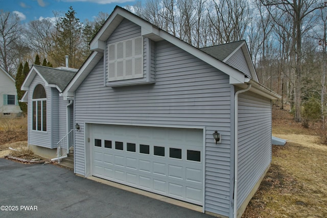 view of home's exterior with aphalt driveway, a garage, and roof with shingles