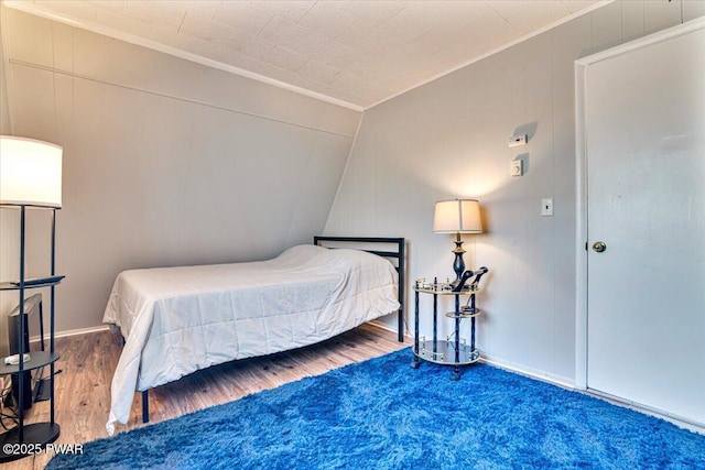 bedroom featuring crown molding, vaulted ceiling, and wood finished floors