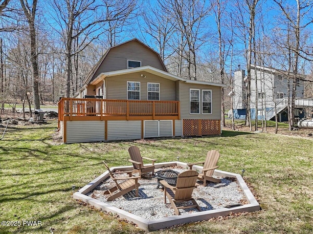 back of house with a lawn, a gambrel roof, a fire pit, and a wooden deck