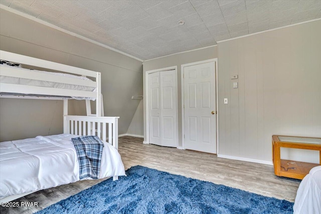 bedroom with crown molding, baseboards, and wood finished floors