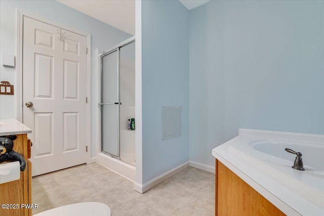 bathroom featuring vanity, a shower stall, and baseboards