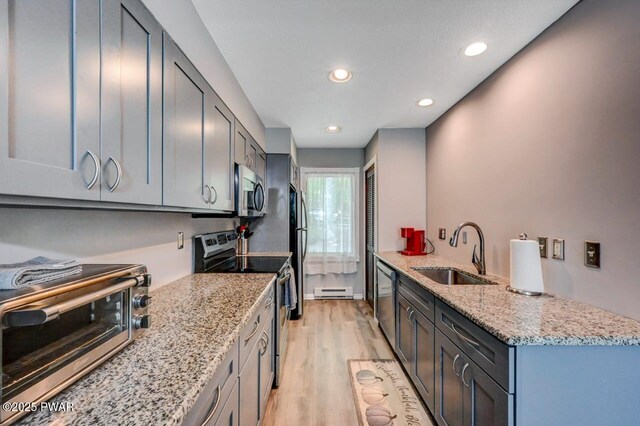 1107 Crest Cir, Lakeville, PA 18438 - kitchen with appliances with stainless steel finishes, a sink, light wood-style flooring, light stone counters, and a peninsula
