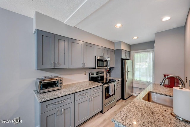 1107 Crest Cir, Lakeville, PA 18438 - kitchen featuring stainless steel appliances, gray cabinetry, a sink, light wood-style floors, and light stone counters
