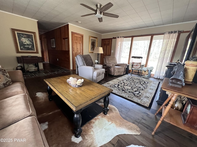 living room featuring wooden walls, ornamental molding, and ceiling fan