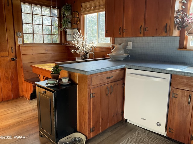 kitchen featuring wooden walls, dishwasher, tasteful backsplash, and hardwood / wood-style floors