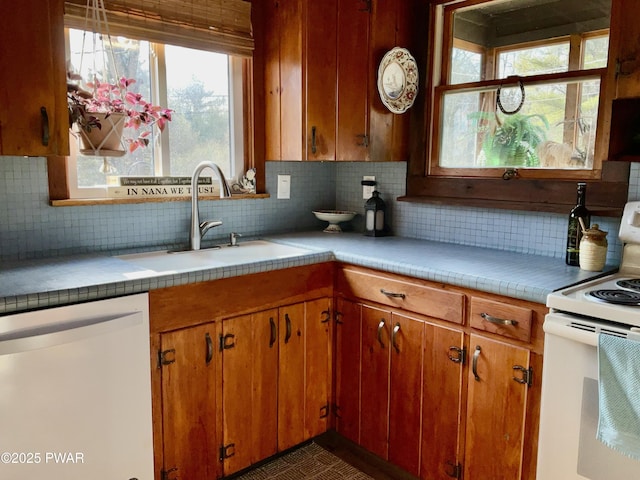 kitchen featuring white appliances, backsplash, sink, and tile counters