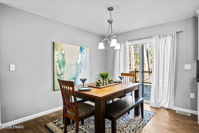 dining space featuring hardwood / wood-style flooring and a chandelier