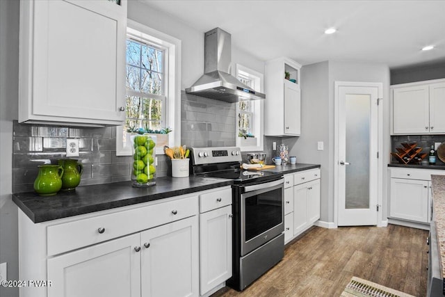 kitchen with wall chimney exhaust hood, stainless steel range with electric cooktop, and white cabinets