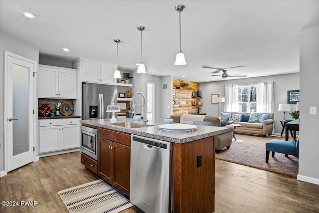 kitchen featuring sink, stainless steel appliances, white cabinets, and a center island with sink