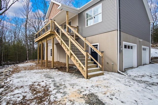 snow covered rear of property featuring a garage