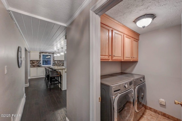 laundry room featuring washer and clothes dryer, cabinet space, baseboards, a textured ceiling, and ornamental molding