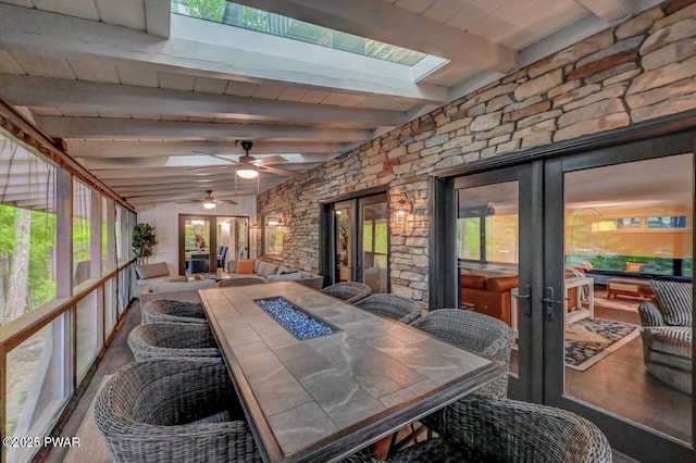 sunroom with french doors, an outdoor fire pit, a ceiling fan, and beamed ceiling
