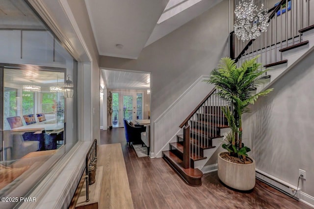 foyer featuring a chandelier, stairway, wood finished floors, baseboard heating, and french doors