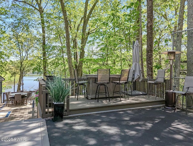 wooden terrace featuring outdoor dining space and a water view