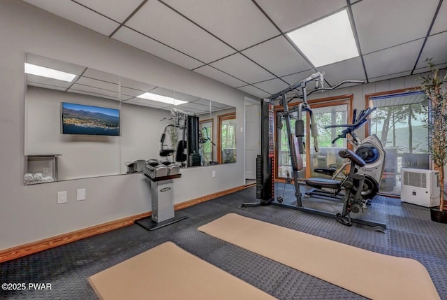 exercise room with a paneled ceiling and baseboards