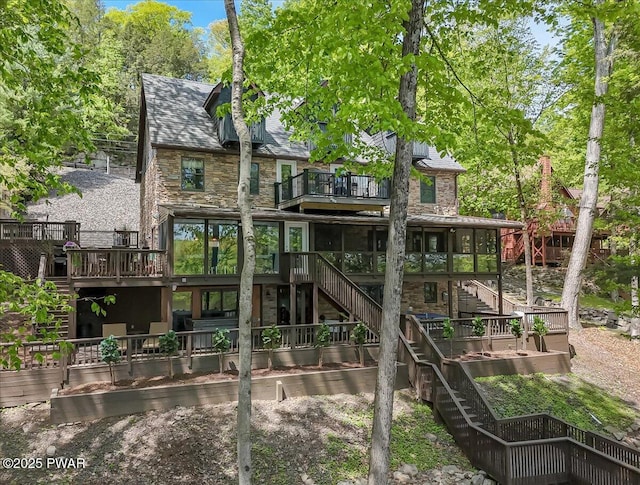 rear view of house with stairs, stone siding, a balcony, and a deck