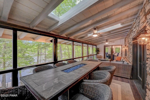 sunroom / solarium featuring a fire pit, outdoor dining area, and ceiling fan