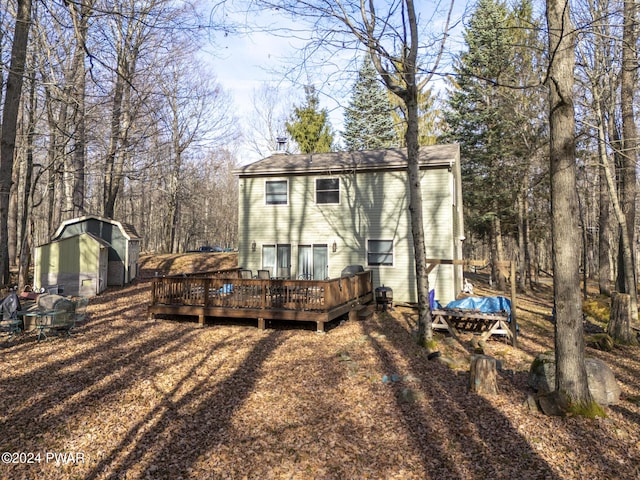 back of house with a shed and a deck