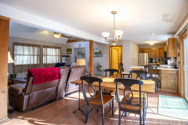 dining space featuring ceiling fan with notable chandelier, lofted ceiling with beams, and light wood-type flooring