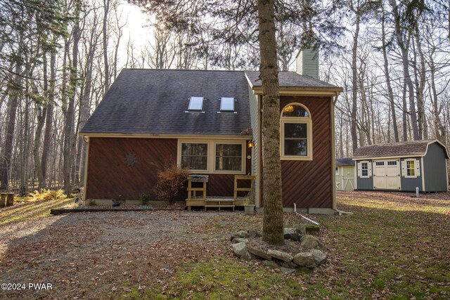 rear view of property featuring a storage shed