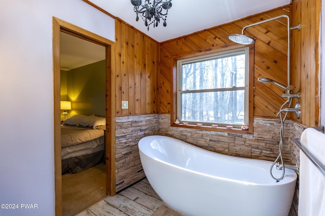 bathroom featuring hardwood / wood-style flooring, a tub, and wooden walls