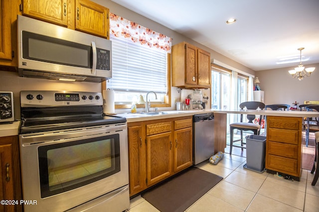 kitchen with sink, stainless steel appliances, a notable chandelier, pendant lighting, and light tile patterned flooring