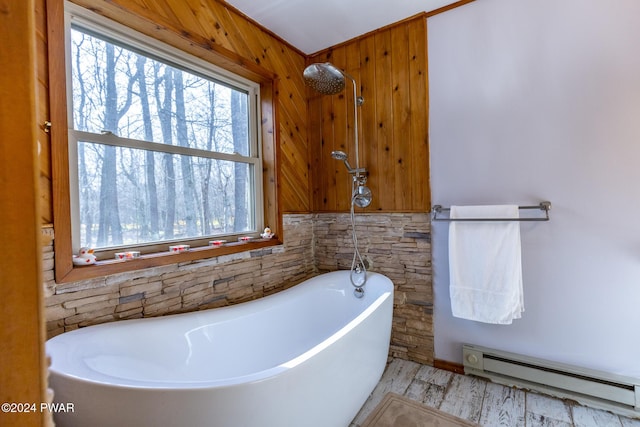 bathroom featuring a bathing tub, wood walls, a baseboard radiator, and hardwood / wood-style flooring