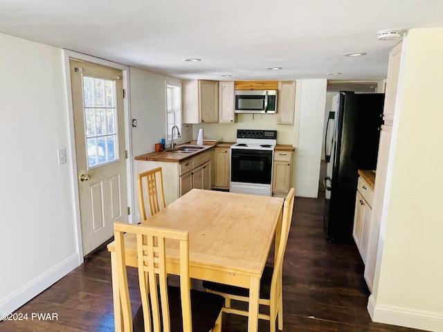 kitchen with white electric range oven, light brown cabinets, dark hardwood / wood-style floors, and black refrigerator