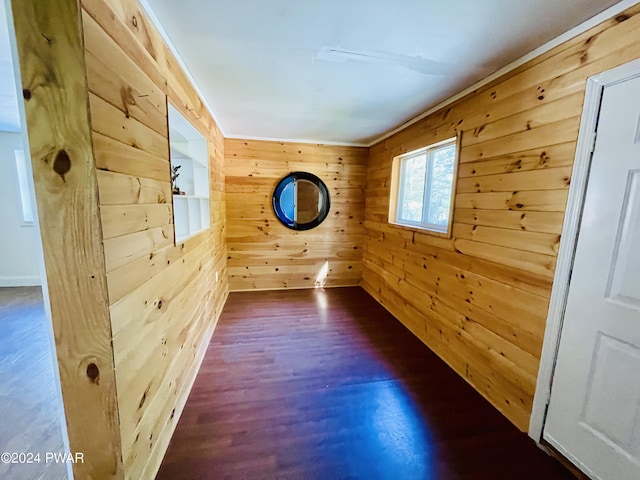 unfurnished room with wood walls, crown molding, and dark hardwood / wood-style floors