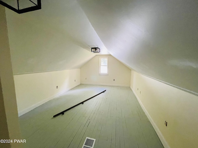 additional living space with hardwood / wood-style floors and lofted ceiling