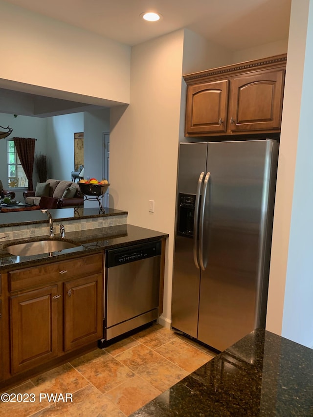 kitchen with appliances with stainless steel finishes, dark stone counters, and sink